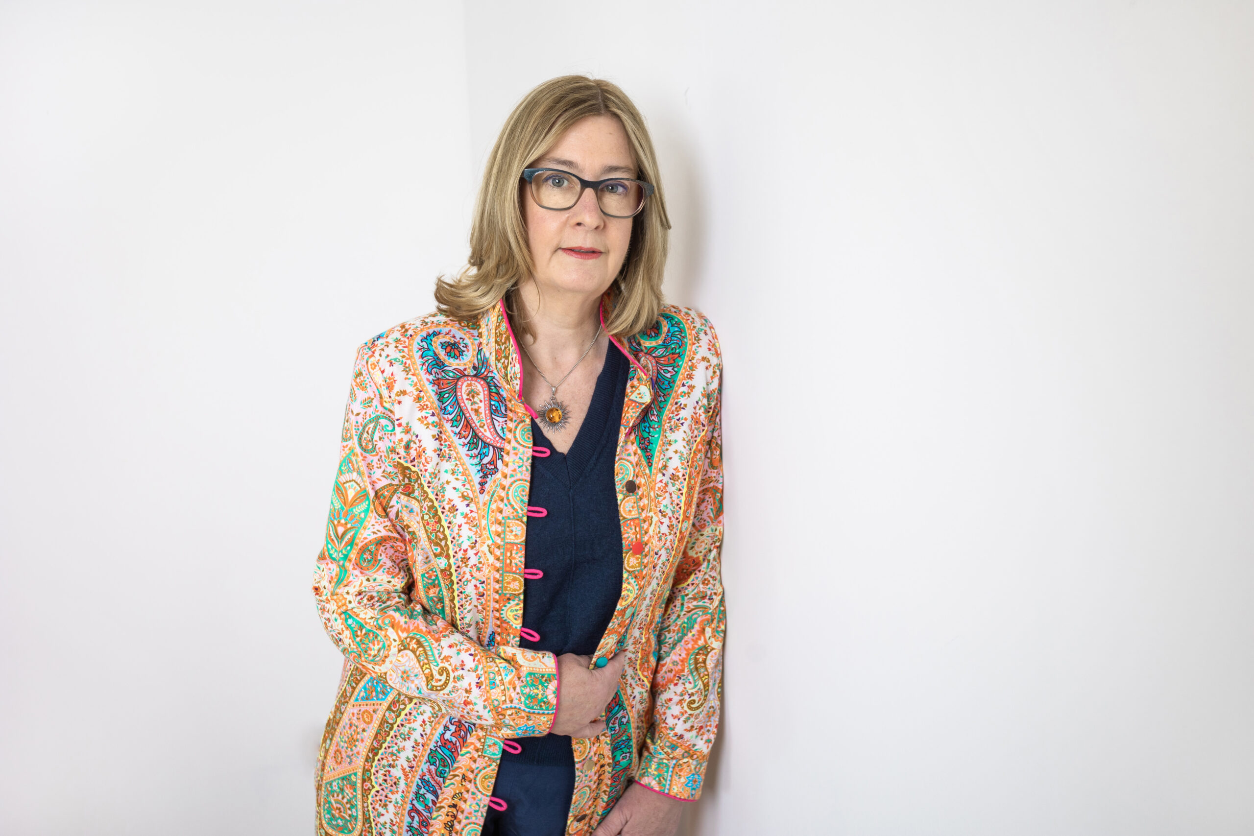 Dr Emma Williams in a colourful patterned jacket, standing and looking at the camera