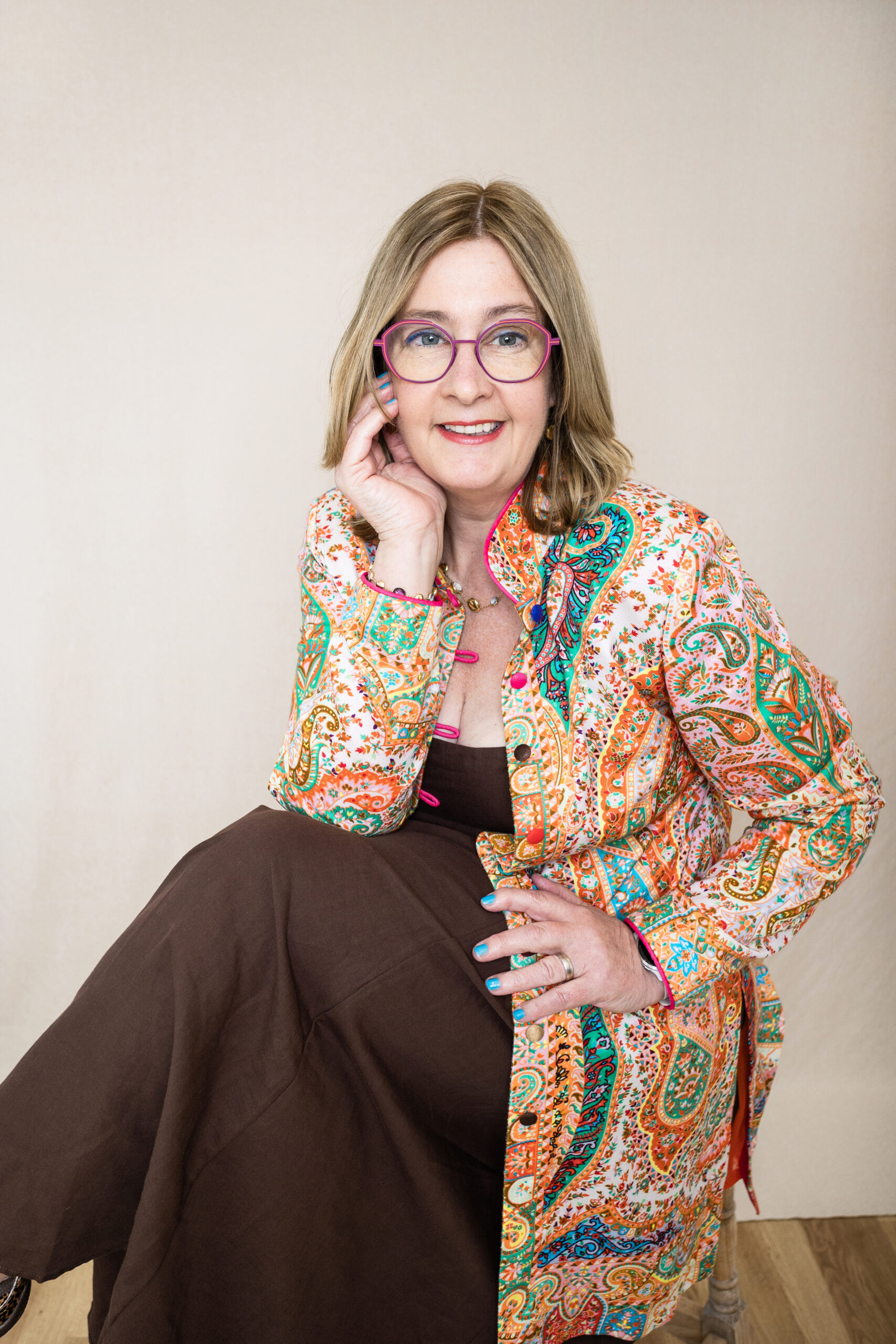 Dr Emma Williams in a patterned jacket, resting her chin on her hand, thinking